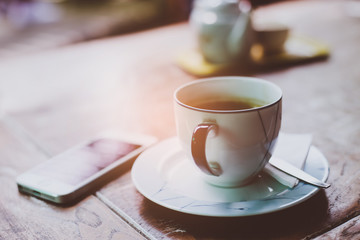 Coffee cup and smartphone on wooden table.