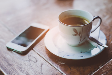cup of coffee and smart phone on wooden table