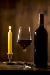 Pouring red wine into wineglass from green bottle