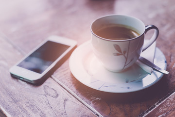 Mobile phone and coffee cup on office wooden table