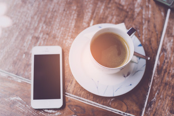 Mobile phone and coffee cup on office wooden table