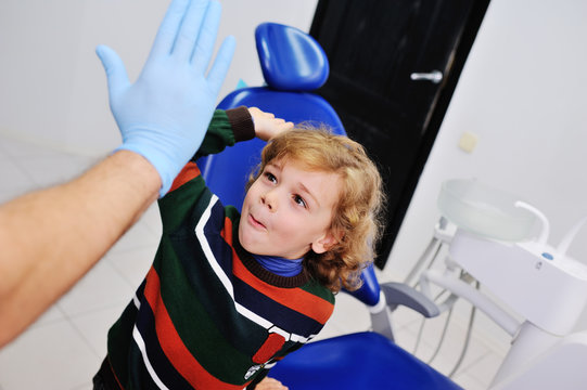 cute child with curly hair gives five dentist. Young boy on dental checkups
