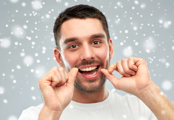 man with dental floss cleaning teeth over snow