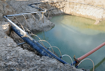 The process of lowering the groundwater level. Industrial sand quarry and a metal tube around it with thin tubes directed at the ground. - 128840561