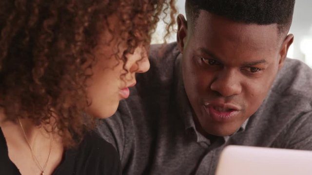 A young black man advises an African American woman while working in a contemporary office