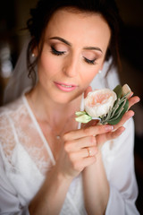 beautiful bride holds a delicate boutonniere for the groom