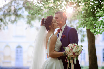 beautiful and young groom and bride kiss each other in the garde