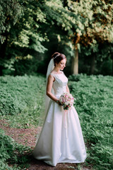 Fototapeta na wymiar happy and beautiful bride in white dress standing outdoors