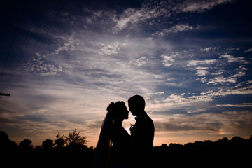 dark silhouettes of groom and bride at sunset