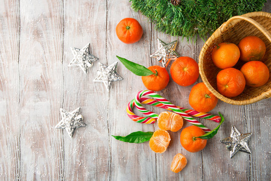 Fresh Tangerines with leaves and Christmas decor with Xmas tree and candies on white old wooden table. Rustic style. Top view. Winter holiday concept