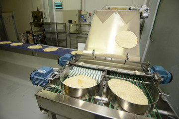 Pizza dough in running on conveyor belt to packaging machine
