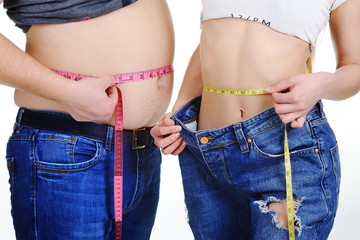 a guy with a big belly and a slim girl measuring waist measuring tape on a white background