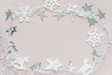 Christmas frame of white christmas decoration: snowflakes, stars, Christmas trees and toy; rocking horse on pink background. Flat lay composition for greeting card, websites, social media, magazines