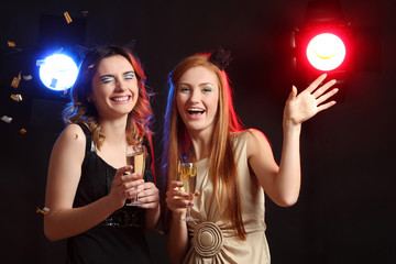 Two cheerful women with glasses of champagne in his hand, having fun at a party.