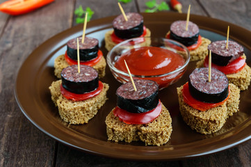 Sandwiches with black rye bread in the shape of a heart, blood sausage (Morcillo) and pieces of...
