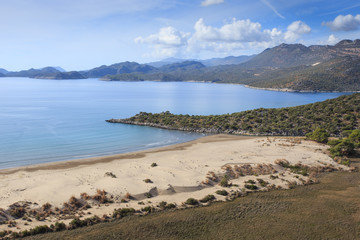 Landscape with a small peninsula, mountains and a sandy beach
