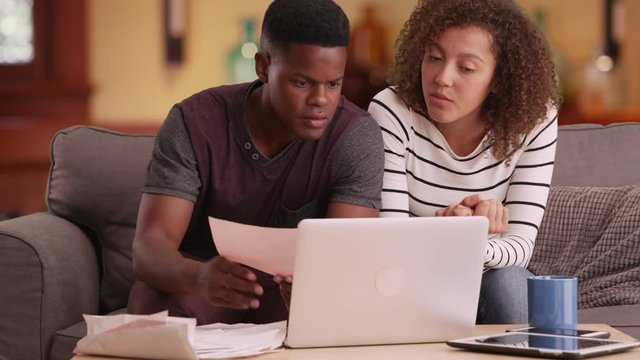 African American couple pays their bills on their laptop
