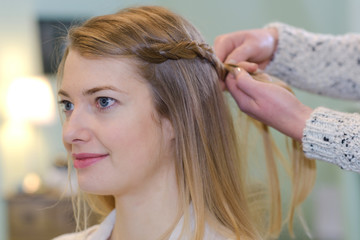 Naklejka premium a hairdresser braiding a client