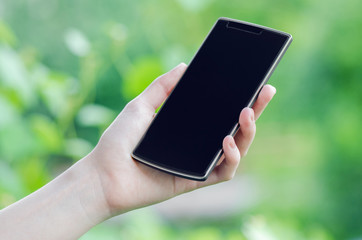 Smart Phone In Hand On Blurry Green Background