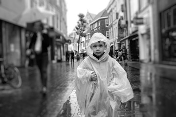 child with his raincoat on pebbles old city in case of rain, the Netherlands