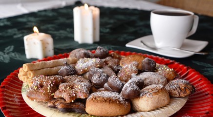 Detail of delicious Christmas cookies with cup of coffee on a table with candle on white tone