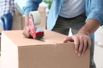 House moving concept. Closeup of man packing cardboard box
