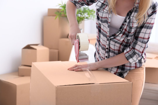 House moving concept. Closeup of woman packing cardboard box