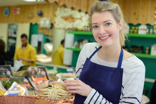 saleswoman offers fresh fish in a shop