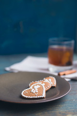 Heart-shaped gingerbread cookies with delicate lace icing on a rustic wooden table.