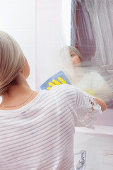 Young lady wiping mirror with special cleaning