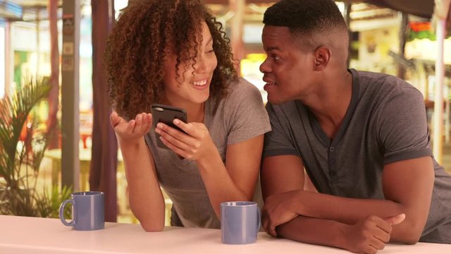 African American couple use their smart phone while at a cafe