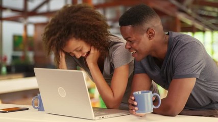 Black millennial couple working together or watching video on laptop in caf_ - Powered by Adobe