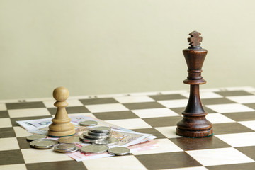 The chess king, pawn and money on a chessboard