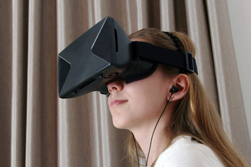 Girl in Virtual Reality headset and sound device looking up and