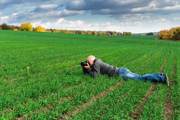 man lying on green field and photographs
