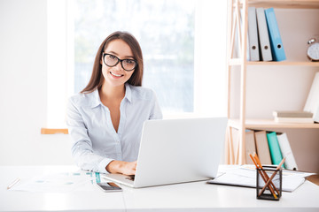 Businesswoman sitting in her office and using laptop