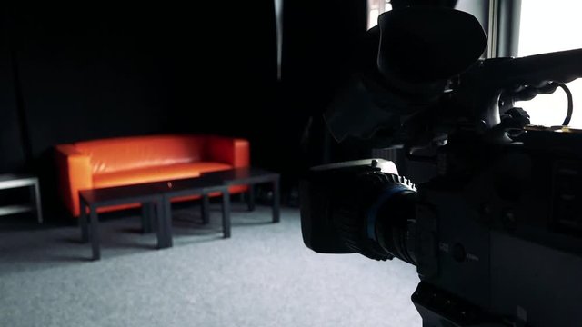 Close - up black camera - sofa in background - studio