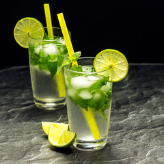 Mojito cocktail with lime and mint in glass on a grey stone background. Square