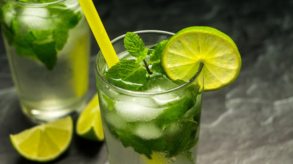 Mojito cocktail with lime and mint in glass on a grey stone background. Copy space