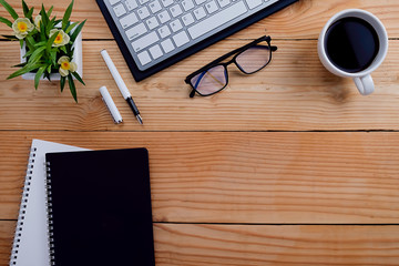 Office desk table with notebook, pen , glasses, keyboard and flower. Top view with copy space (selective focus)