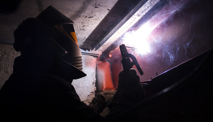 Welder in a protective mask works with metal