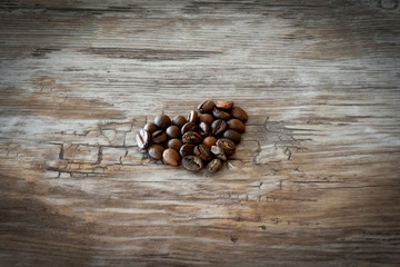 Heart shape made from coffee beans on wooden background.