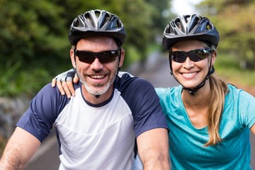 Fototapeta na wymiar Athletic couple wearing helmets while riding bicycle