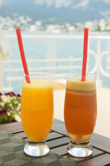 wo glasses with juice on the table near the sea