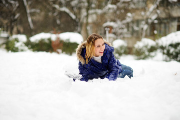 Fototapeta na wymiar White Christmas. Cheerful young woman lies on snow and holds a snowball in hand.