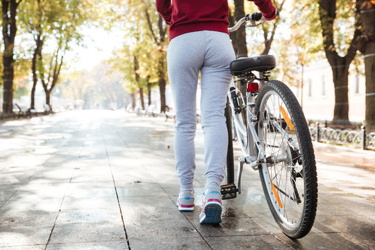 Cropped image of young woman walking with bicycle