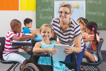 Schoolgirl and teacher using digital tablet in classroom