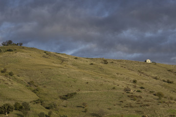 Collina con casolare e nuvole