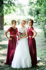 happy and young bride and her bridesmaids standing together