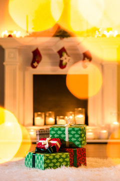 Some cute new year gifts brightly wrapped, fireplace and candles on the background, sunny bunnies playing on the picture. Christmas presents against lights background, copy space.